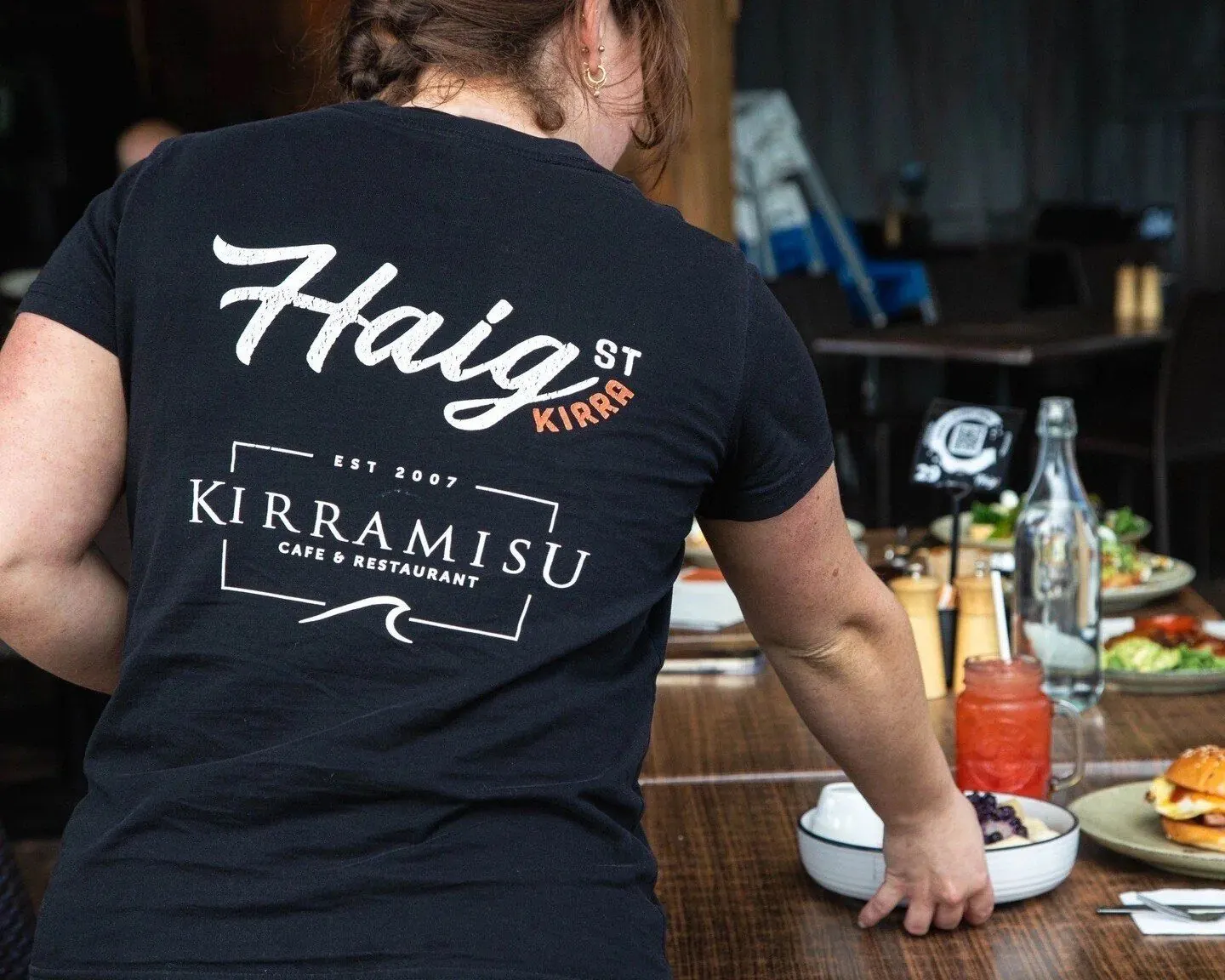 Haig Street Kirra staff in branded tee serving a full table
